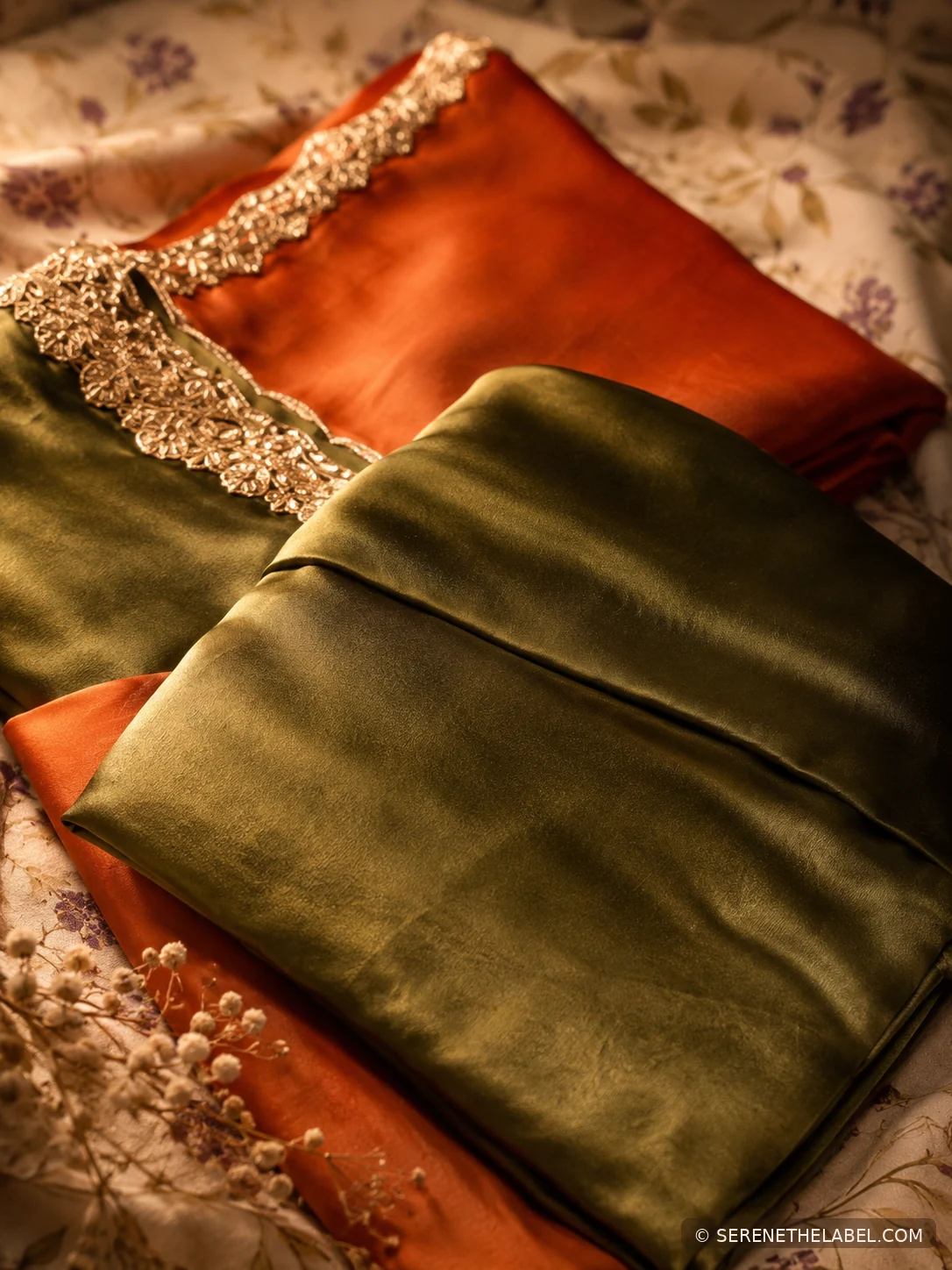 Folded silk fabrics in warm rust and olive tones with embellished trim